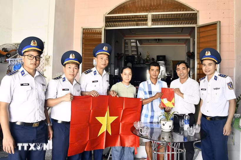 Các lực lượng chức năng trao cờ và hướng dẫn cho ngư dân khai thác hải sản đúng pháp luật. (Ảnh: Trần Tĩnh/TTXVN)