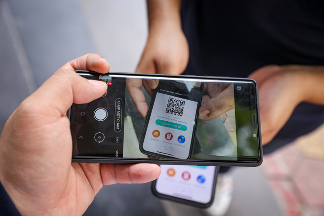 Người dân sử dụng mã QR để quét mỗi khi ra vào các cơ sở kinh doanh tại Hà Nội. (Ảnh: Minh Sơn/Vietnam+) Quét mã QR - 'chìa khoá' chống dịch khi nới lỏng giãn cách tại Thủ đô ảnh 1