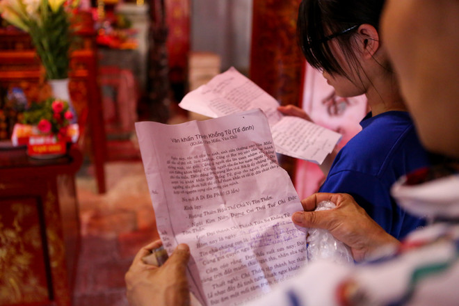 Một số phụ huynh còn cẩn thận mang theo văn khấn, hồ sơ thi của con, ghi rõ số báo danh, phòng thi để khấn cho rõ ràng, mong các bậc tiền nhân phù hộ đạt kết quả tốt trong những kỳ thi ngày mai. (Ảnh: Minh Sơn/Vietnam+) Sĩ tử Hà Nội nô nức đến Văn Miếu cầu may trước ngày thi vào lớp 10 ảnh 8