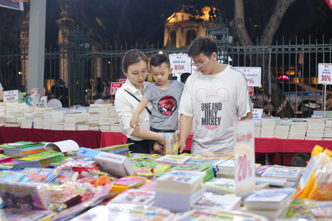 Gia đình anh Hiểu chị Vân nhà ở gần Văn Miếu - Quốc Tử Giám ngay khi biết tin có Hội sách đã đưa con mình đến tham quan các gian hàng. Chị Vân chia sẻ, hai vợ chồng thường xuyên dùng sách điện tử nhưng hiện tại đang muốn cho con mình tiếp cận với sách giấy để làm quen và hình thành thói quen đối với sách.(Ảnh: Diễm Hằng/Vietnam+) vnp_ngay sach va van hoa doc-5.jpg