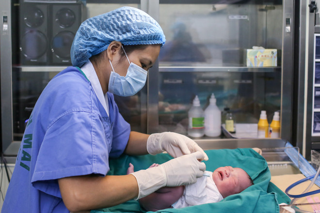 Trong khi bé Nam Anh được các y tá chăm sóc thì các bác sĩ của ca mổ vẫn đang miệt mài tiến hành bóc nhau thai, làm sạch buồng tử cung và khâu lại vết mổ. (Ảnh: Minh Sơn/Vietnam+) Lặng người trước hình ảnh vượt cạn đầy cảm xúc của bà mẹ Việt ảnh 11
