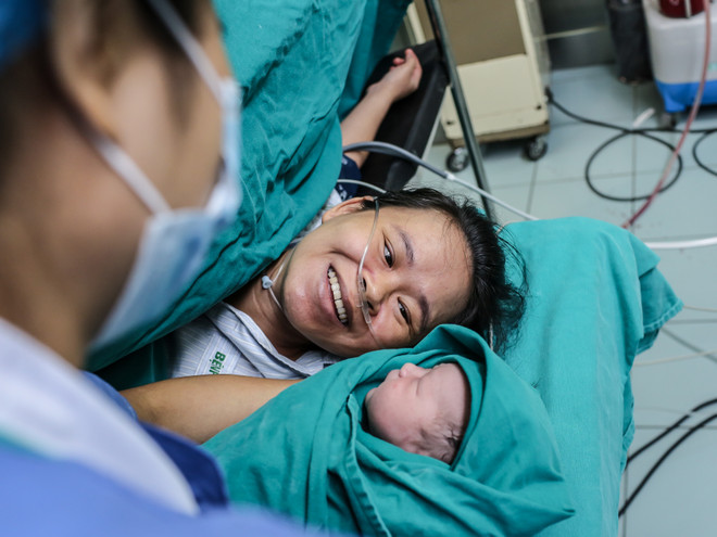 Khoảnh khắc hạnh phúc tột cùng của chị Nguyễn Thị Mỹ Hạnh khi ngắm nhìn đứa con trai mới chào đời mạnh khỏe. (Ảnh: Minh Sơn/Vietnam+) Lặng người trước hình ảnh vượt cạn đầy cảm xúc của bà mẹ Việt ảnh 1