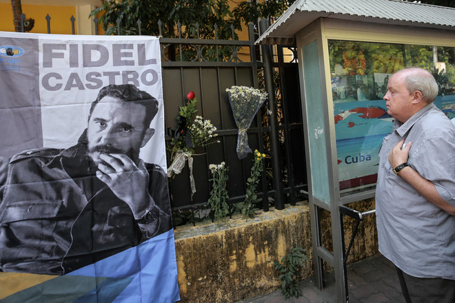 Một người đàn ông nghiêm trang đặt hoa cạnh bức ảnh nhà lãnh tụ vĩ đại Fidel Castro. (Ảnh: Minh Sơn/Vietnam+) Lễ viếng cảm động Lãnh tụ Fidel Castro tại Đại sứ quán Cuba ảnh 1
