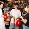 Du khách quốc tế hào hứng vì được tặng lá cờ đỏ sao vàng khi trải nghiệm điểm đến Thành phố Hồ Chí Minh. (Ảnh: CTV/Vietnam+)