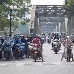 Người dân thành phố Huế mặc đồ bảo hộ chống nắng khi, di chuyển ở phía Bắc cầu Trường Tiền, phường Phú Xuân. (Ảnh: Nguyên Lý/TTXVN)