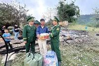 Cán bộ Đồn Biên phòng Ba Nang đến thăm hỏi, động viên và hỗ trợ bằng tiền mặt cùng các nhu yếu phẩm thiết yếu cho hộ dân bị cháy nhà. (Ảnh: TTXVN phát)