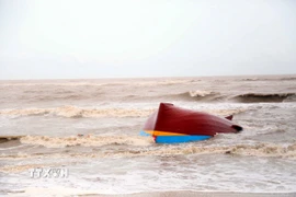 Một tàu cá bị lật úp, dạt vào bờ biển, cách khu vực cảng Gianh (xã Bắc Trạch, Quảng Trị) khoảng gần 3 km. (Ảnh: Tá Chuyên/TTXVN)