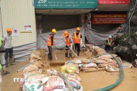 Công nhân đang nỗ lực khắc phục sự cố trước cổng số nhà 25F Cát Linh. (Ảnh: Thành Phương/TTXVN)