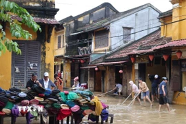 Người dân dọn bùn tại ngã tư Nguyễn Thái Học-Lê Lợi, phường Hội An. (Ảnh: Kha Phạm/TTXVN)