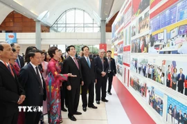 Bí thư Đảng ủy, Tổng Giám đốc TTXVN Vũ Việt Trang giới thiệu với Chủ tịch nước Lương Cường, nguyên Thủ tướng Nguyễn Tấn Dũng và các đại biểu tham quan triển lãm ảnh về Đại hội. (Ảnh: TTXVN)