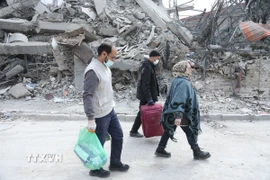 Người dân đi qua đống đổ nát của những tòa nhà bị phá hủy tại Tehran, Iran. (Ảnh: THX/TTXVN)