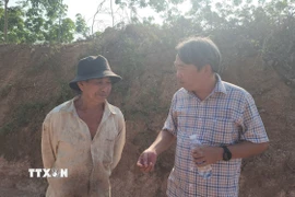 Đoàn kiểm tra kiểm tra thực tế khu vực nhà dân bị ảnh hưởng, lắng nghe ý kiến và hướng dẫn người dân viết đơn đề xuất nguyện vọng. (Ảnh: Đậu Tất Thành/TTXVN)