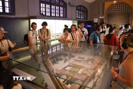 Du khách sử dụng bộ đàm thuyết minh tự động khi tham quan di tích Nhà tù Hỏa Lò, Hà Nội. (Ảnh: Thanh Tùng/TTXVN)