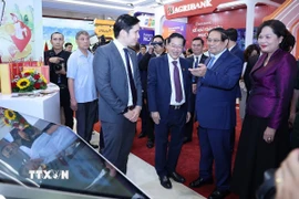 Thủ tướng Phạm Minh Chính tham quan trưng bày sản phẩm dịch vụ, ứng dụng chuyển đổi số trong hoạt động ngân hàng. (Ảnh: Dương Giang/TTXVN)