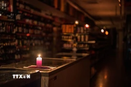 Thắp nến trong cửa hàng ở Barcelona, Tây Ban Nha khi điện bị mất trên diện rộng. (Ảnh: THX/TTXVN)
