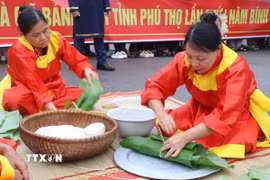 Các nghệ nhân thực hiện gói bánh chưng tại Hội thi. (Ảnh: Thu Hương/TTXVN)