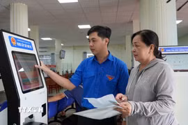 Thanh niên tình nguyện phường Rạch Giá, An Giang, hướng dẫn người dân đăng ký giải quyết thủ tục hành chính trên hệ thống. (Ảnh: Văn Sĩ/TTXVN)