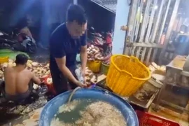 Nhân viên cơ sở sơ chế hoa chuối thực hành lại quá trình pha hóa chất vào nước ngâm hoa chuối. (Ảnh: Công an cung cấp)