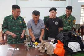 Cán bộ Đồn Biên phòng Mỹ Quý Tây kiểm tra đối tượng cùng tang vật. (Ảnh: TTXVN phát)