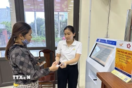 Cán bộ phường Vĩnh Phúc, tỉnh Phú Thọ hỗ trợ người dân đăng ký, lấy số khi làm thủ tục hành chính. (Ảnh: Nguyễn Thảo/TTXVN)