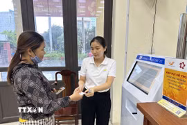 Cán bộ phường Vĩnh Phúc, tỉnh Phú Thọ hỗ trợ người dân đăng ký, lấy số khi làm thủ tục hành chính. (Ảnh: Nguyễn Thảo/TTXVN)