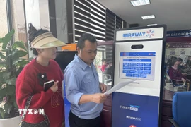 Cán bộ hướng dẫn thủ tục lấy số cho người dân tại Trung tâm Dịch vụ công Thành phố Vinh. (Ảnh: Bích Huệ/TTXVN)