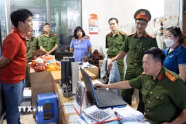Lực lượng chức năng khám xét nơi làm việc của các bị can. (Ảnh: TTXVN phát)