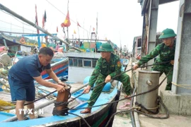 Lực lượng Bộ đội biên phòng tỉnh Nghệ An hỗ trợ giúp ngư dân chằng néo tàu thuyền tại nơi tránh trú bão an toàn. (Ảnh: TTXVN phát)