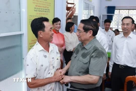 Thủ tướng Phạm Minh Chính thăm hỏi nhân dân thực hiện thủ tục hành chính tại Trung tâm phục vụ hành chính công phường Thới Sơn, tỉnh An Giang. (Ảnh: Dương Giang/TTXVN)
