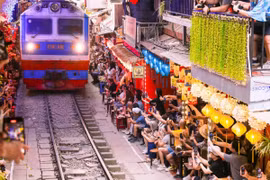 Du khách chen chúc tại các quán càphê hai bên đường ray, háo hức chụp ảnh và tận hưởng cảm giác hồi hộp khi tàu đến. (Ảnh: Ngọc Anh/TTXVN phát)