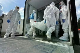 Các nhân viên chuyển thi thể binh sỹ Ukraine từ xe vận chuyển đông lạnh để hồi hương gần Novaya Guta, Belarus vào ngày 19/8. (Nguồn: AP)