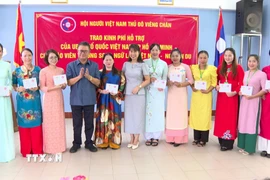 Đại diện Đại sứ quán Việt Nam tại Lào và Hội người Việt Nam thủ đô Vientiane trao quà cho các thầy cô giáo. (Ảnh: Bá Thành/TTXVN)
