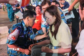 Bác sỹ quân y hỗ trợ kiểm tra sức khoẻ cho người dân bị tụt huyết áp, khó thở khi chờ đợi lâu trong đám đông và thời tiết không thuận lợi trong đêm 29, rạng sáng 30/8. (Ảnh: Hoàng Hiếu/TTXVN)