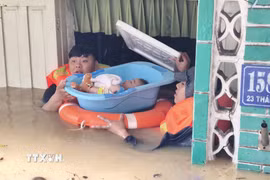 Lực lượng chức năng hỗ trợ đưa trẻ em ra khỏi căn nhà bị ngập sâu ở phường Tây Nha Trang (Khánh Hòa). (Ảnh: Nguyễn Thành/TTXVN)