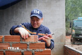 Trung úy Bùi Quang Vinh, Phòng Cảnh sát Phòng cháy, chữa cháy và cứu nạn, cứu hộ (Công an thành phố Đà Nẵng) tham gia xây nhà cho bà con bị ảnh hưởng của bão lũ tại xã Nam Trà My, thành phố Đà Nẵng. (Ảnh: Quốc Dũng/TTXVN)