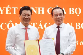 Bí thư Thành ủy Thành phố Hồ Chí Minh Nguyễn Văn Nên (bìa phải) trao Quyết định của Bộ Chính trị cho ông Nguyễn Mạnh Hùng. (Ảnh: Thanh Tân/TTXVN)