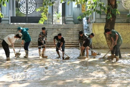 Người dân dọn bùn đất trên các tuyến đường ở phường Hà Giang 1 (Tuyên Quang). (Ảnh: Đức Thọ/TTXVN)