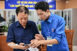 Đoàn viên thanh niên hướng dẫn người dân sử dụng, khai báo, các dịch vụ công trực tuyến trên điện thoại thông minh. (Ảnh: Hoàng Hiếu/TTXVN)