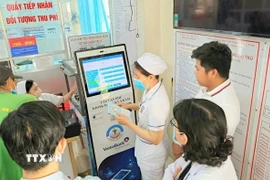 Cán bộ, nhân viên Trung tâm y tế An Phú, An Giang, hướng dẫn người dân đăng ký khám chữa bệnh bằng kiốt thông minh. (Ảnh: Công Mạo/TTXVN)