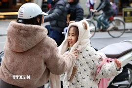 Trẻ em được giữ ấm khi lưu thông bằng xe máy trong những ngày rét đậm. (Ảnh: Vũ Quang/TTXVN)