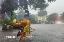 Khẩn trương tiêu thoát nước trên đường Bà Triệu. (Ảnh: Nguyễn Thắng/TTXVN)