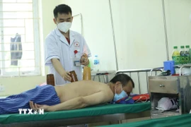Sử dụng phương pháp giác hơi điều trị cho bệnh nhân. (Ảnh: Anh Tuấn/TTXVN)