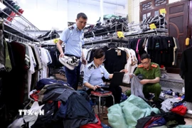 Lực lượng quản lý thị trường tỉnh Tuyên Quang kiểm tra, lập biên bản một cửa hàng kinh doanh quần áo có dấu hiệu giả mạo nhãn hiệu tại phường Minh Xuân, thành phố Tuyên Quang. (Ảnh: Quang Cường/TTXVN)