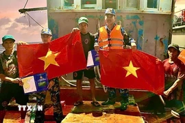 Cán bộ, chiến sỹ Vùng 2 Hải quân tuyên truyền, tặng cờ cho ngư dân trên biển. (Ảnh: TTXVN phát)