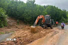 Lực lượng chức năng thu dọn vị trí bị sạt lở trên tuyến đường Quốc lộ 14G, xã Hòa Vang. (Ảnh: TTXVN phát)