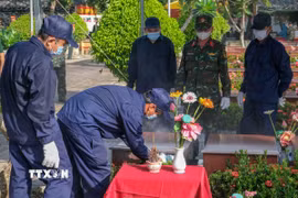 Lực lượng chuyên môn tiến hành đưa hài cốt liệt sỹ ra khỏi mộ để lấy mẫu giám định. (Ảnh: Thanh Liêm/TTXVN)
