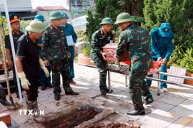 Hài cốt liệt sỹ được hoàn táng đúng vị trí ban đầu trong các phần mộ tại nghĩa trang sau khi lấy mẫu sinh phẩm. (Ảnh: Nguyễn Lành/TTXVN)
