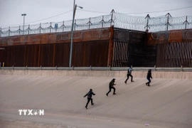 Những người di cư chuẩn bị vượt qua bức tường biên giới Mỹ-Mexico. (Ảnh: THX/TTXVN)