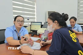 Công chức phường Mạo Khê, Quảng Ninh, hướng dẫn công dân nộp hồ sơ chứng thực lên Cổng dịch vụ công Quốc gia. (Ảnh: Thanh Vân/TTXVN)