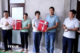 Tổng Giám đốc TTXVN Vũ Việt Trang tặng quà cho gia đình được TTXVN hỗ trợ xây dựng nhà mới. (Ảnh: Quang Cường/TTXVN)